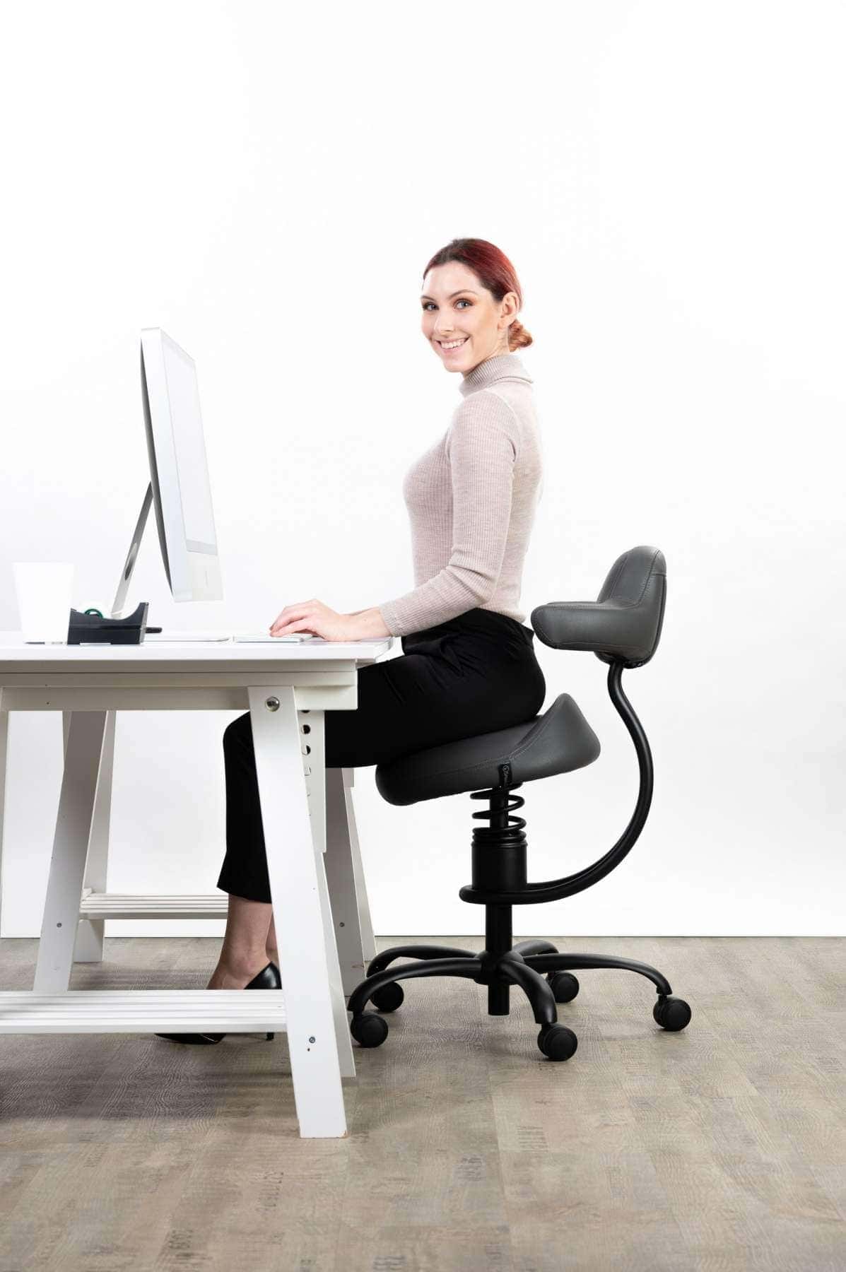 Punca sedi na sivem pisarniškem stolu in dela z računalnikom