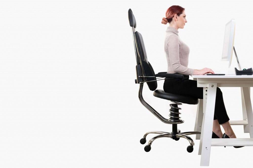 Eine Frau sitzt auf einem Bürostuhl als Pilotin an ihrem Schreibtisch