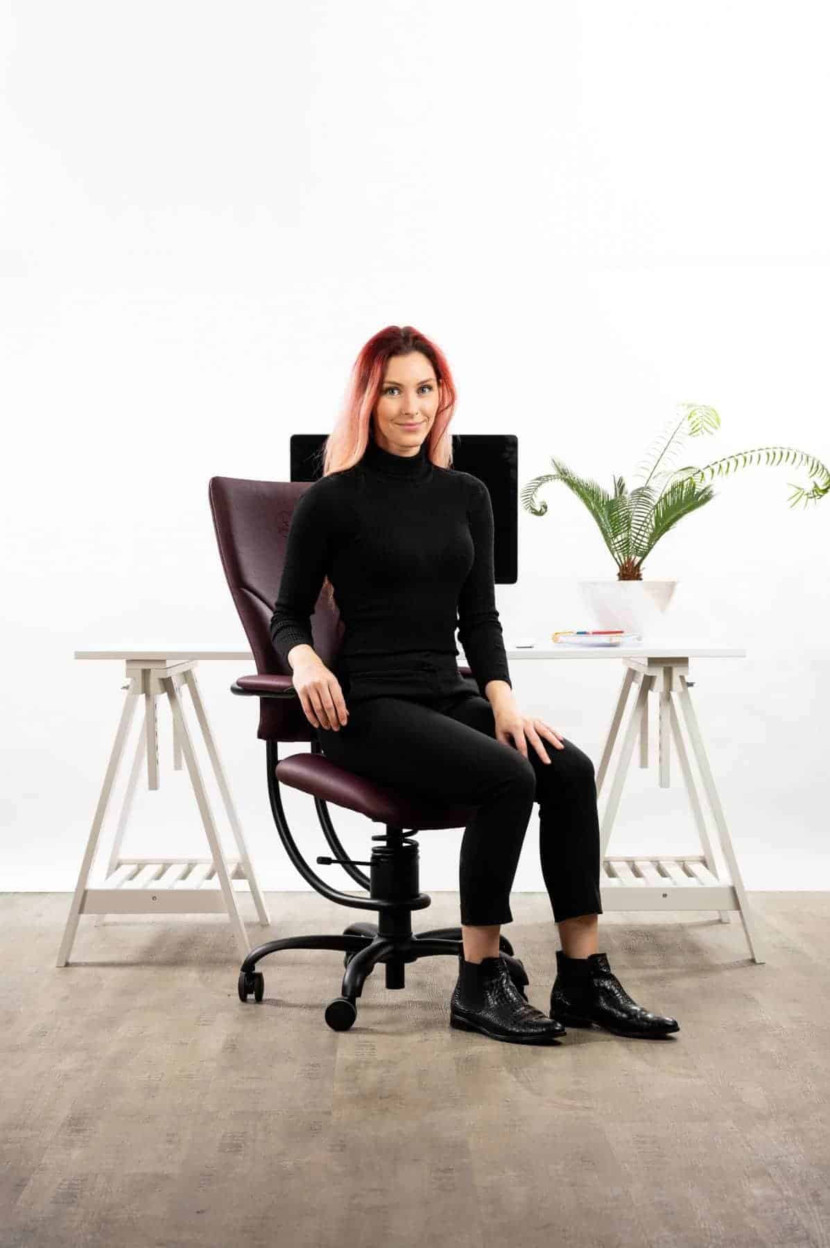 Ženska sedi na pisarniškem stolu Apollo rdeče barve