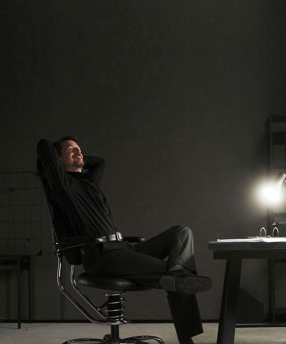 Moški sedi sproščeno na pisarniškem stolu